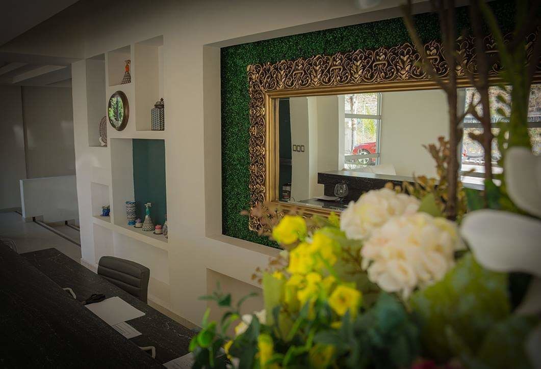 A modern room with a large mirror, a desk, and a green accent wall.