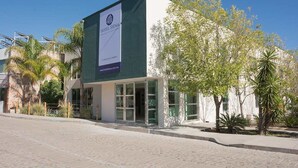 A modern hotel with a prominent sign, large windows, and a paved entrance area. - Hotel Siena (Penjamo)