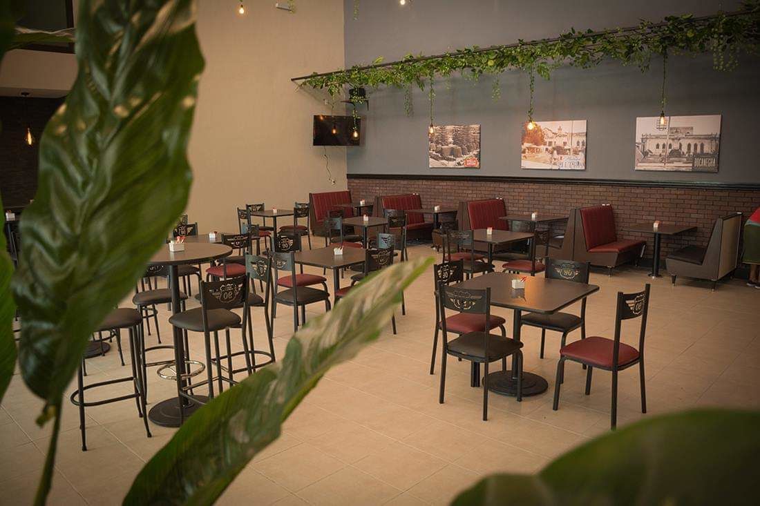 Un restaurant avec plusieurs tables et chaises, dont certaines sont dotées de coussins rouges.