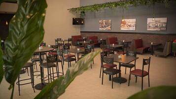 Un restaurant avec plusieurs tables et chaises, dont certaines sont dotées de coussins rouges.