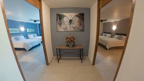 A hallway with two bedrooms, each with a bed and a nightstand. There is a wooden table with a vase of flowers in the center. - Hotel Siena (Penjamo)