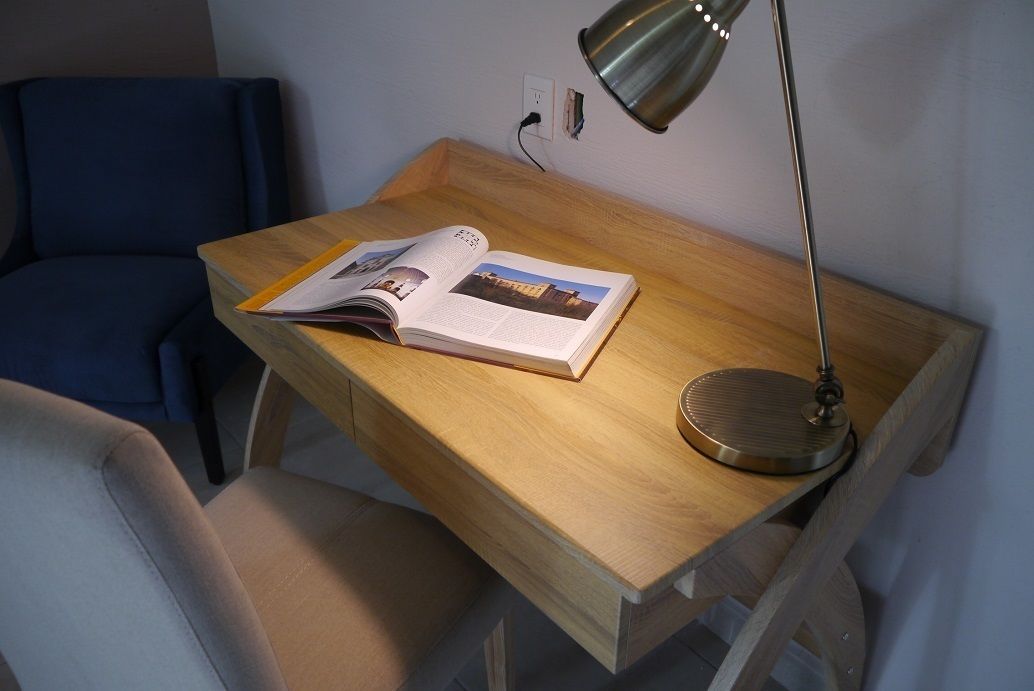 Et træskrivebord med en bog og en lampe.