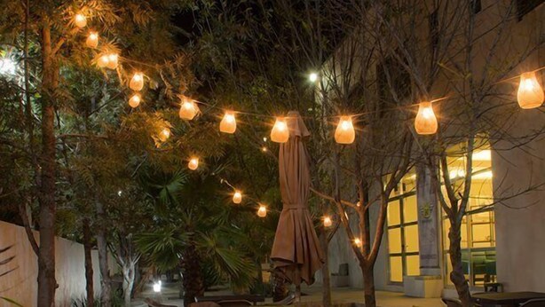 An outdoor patio area with tables and chairs, string lights, and umbrellas. - Hotel Siena (Penjamo)