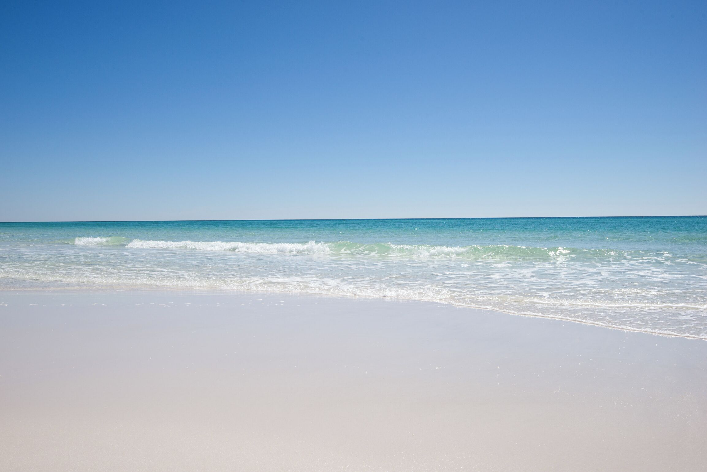 A beach with clear skies and calm waves.