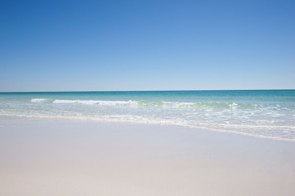 Ein Strand mit blauem Himmel und ruhiger Welle.