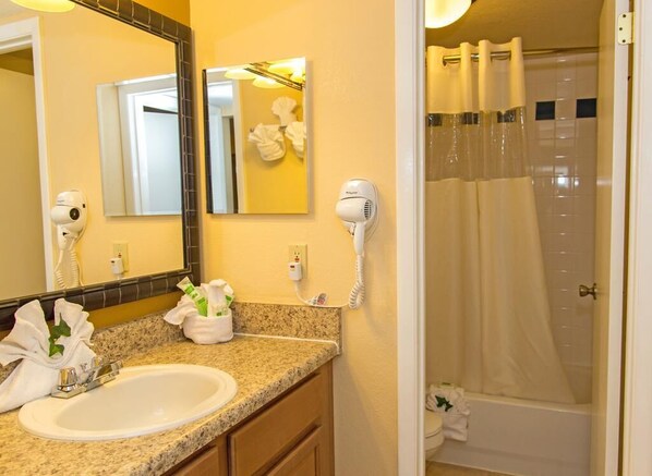 A bathroom with a sink, two hair dryers, a mirror, and a shower curtain. - **FULLY RENOVATED** PERFECT RESORT CONDO CLOSE TO SEAWORLD AND OUTLETS (Orlando)