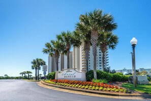 Ein Hotelschild mit 'Ariel Duness II' und '122 Seaside Blvd.'. Das Hotel wird von Palmen umgeben und verfügt über einen gepflegten Garten mit roten Blumen.