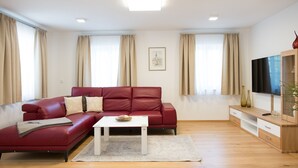 Ein modernes Wohnzimmer mit einem roten Sofa, einem weißen Couchtisch und einer Holz-TV-Konsole.