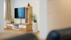 Ein modernes Wohnzimmer mit einer Holztrennwand, einem Flachbildfernseher und dekorativen Vasen.