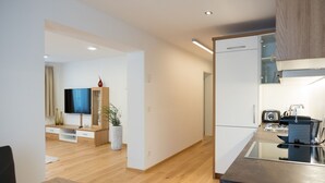 Eine moderne Küche mit Einbauofen, Spüle und Toaster. Ein Holztisch mit Stühlen steht daneben.