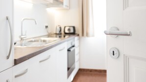 A modern kitchen with white cabinetry, a stainless steel sink, and a built-in oven.