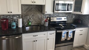 A modern kitchen with white cabinets, a stainless steel refrigerator, a microwave, and a stove. - "THE PLACE AT SUNRISE BEACH" (Marshfield)