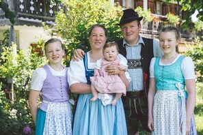 A family in traditional attire standing in a garden with a building in the background.