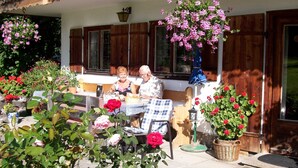 Een terras met een tafel, stoelen en potplanten.
