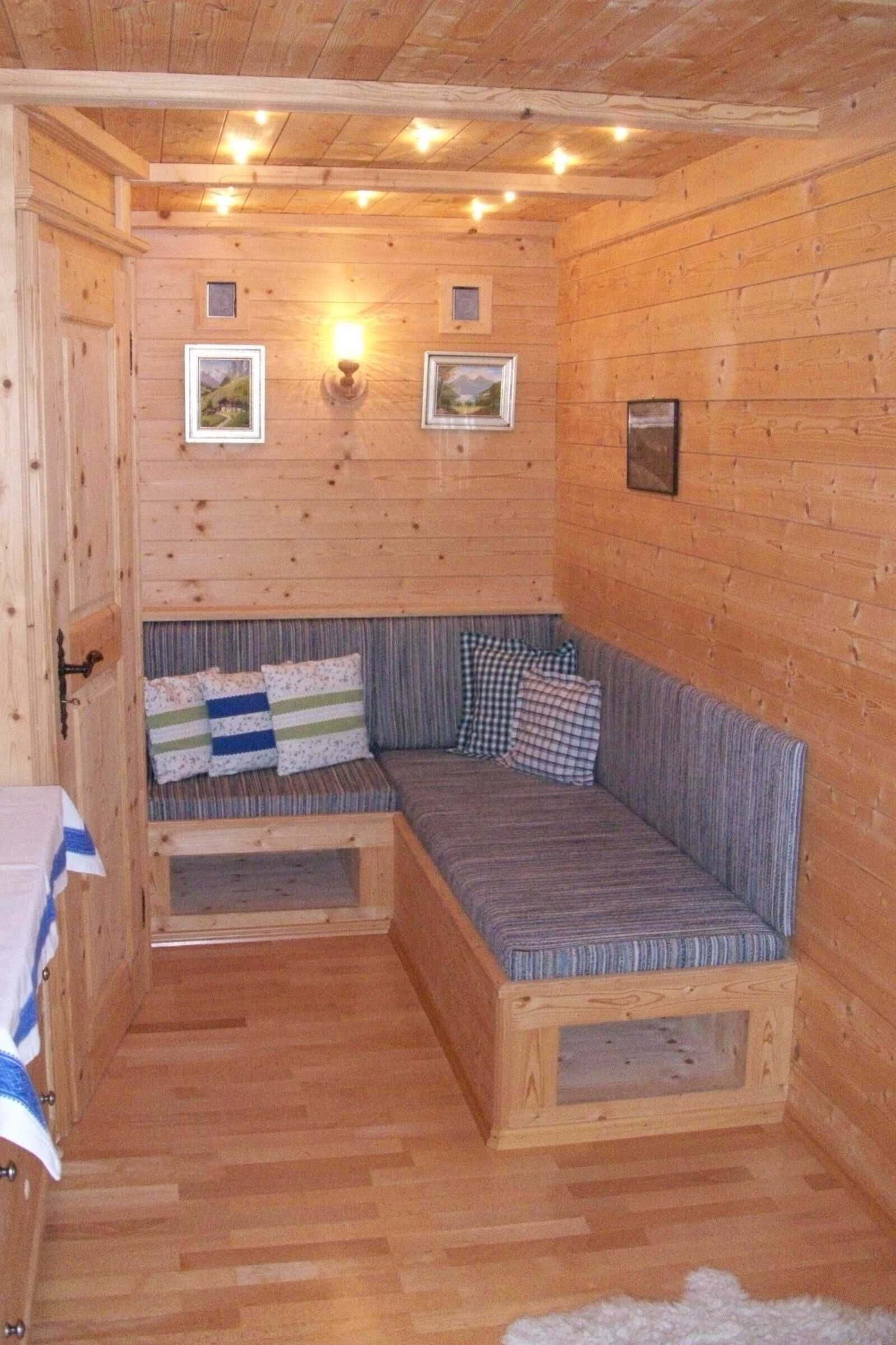 Ein Holzblockhaus-Innenraum mit integriertem Sitzplatz, Wandleuchten und gerahmten Bildern.