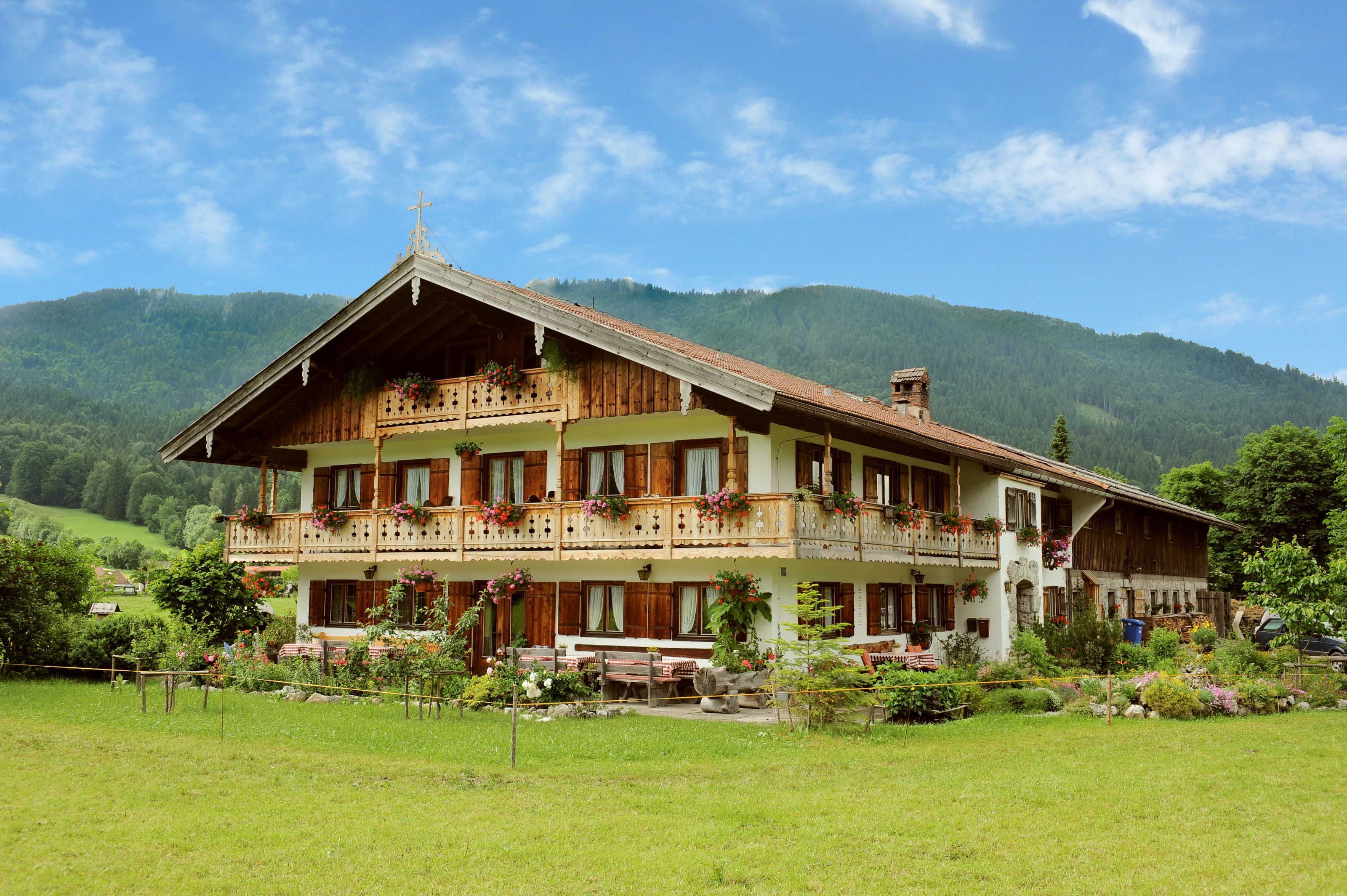 Un chalet à deux étages doté de balcons, d’une façade en bois et surplombant un paysage montagneux.