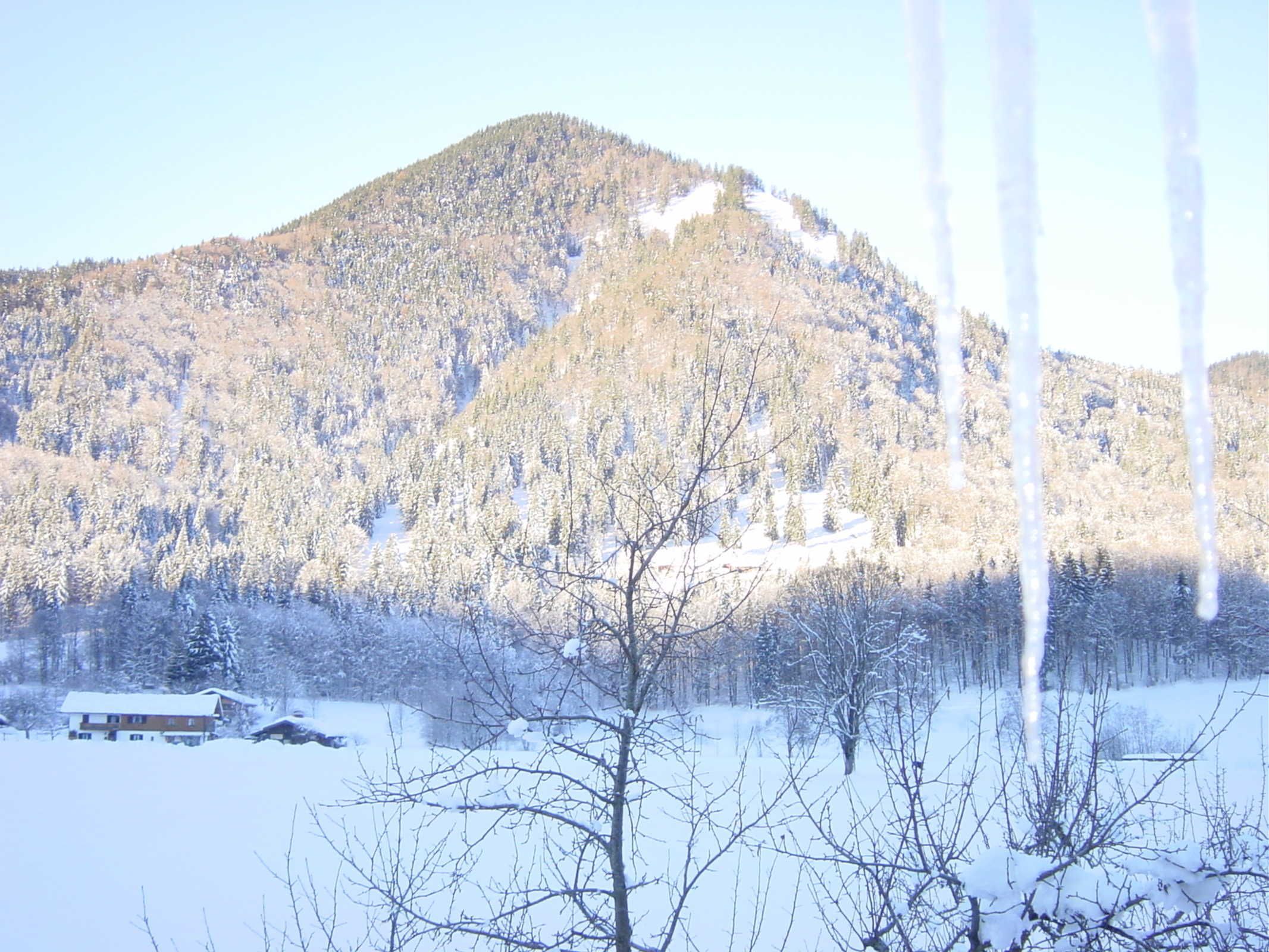 A snowy mountain landscape with a house in the foreground.