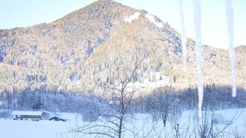 A snowy mountain landscape with a house in the foreground.