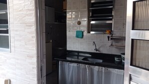 A compact kitchen with a built-in oven, a sink, and a small window. - Family home (Sítio do Campo)