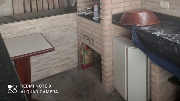 A rustic kitchen with a brick oven, a window with bars, and a stone wall. - Family home (Sítio do Campo)