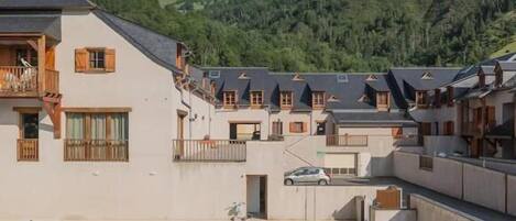 Un hotel con piscina, varios balcones y vistas a las colinas circundantes.