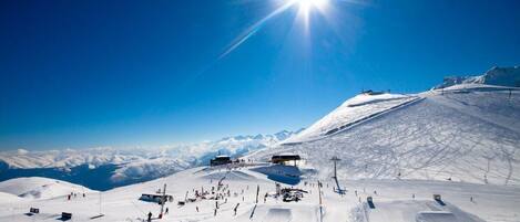 Pista de esquí nevada con cielo despejado y sol brillante.