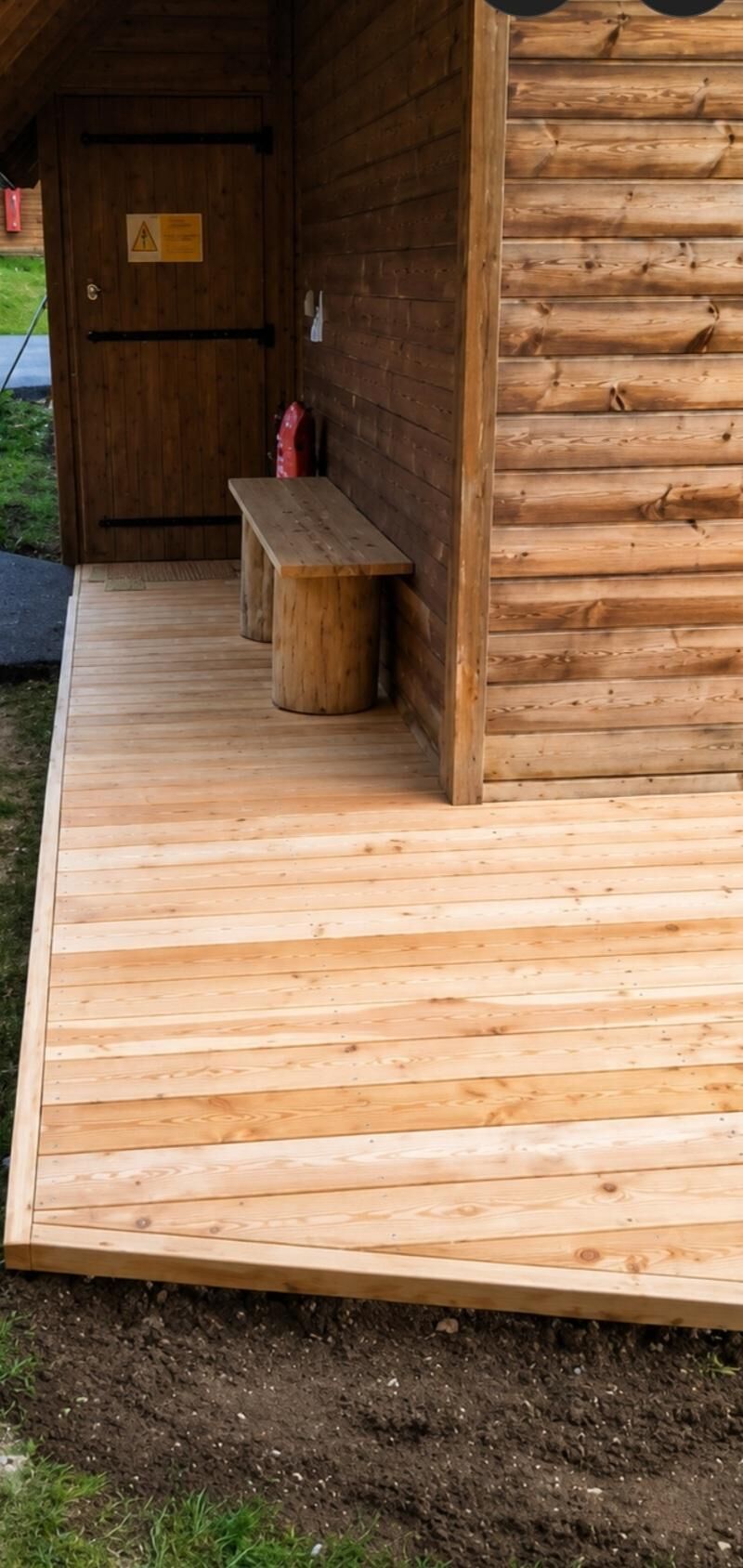 Une cabane en bois avec un banc et une porte.