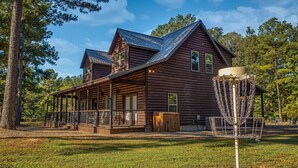 A rustic log cabin with a porch and a disc golf basket.
