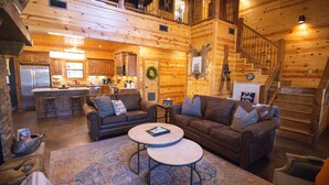 A log cabin interior with a kitchen, two sofas, a coffee table, and a rug.