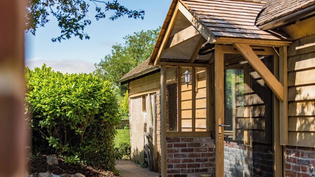 A wooden house with a brick exterior, a covered porch, and a small garden area.