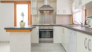 A modern kitchen with white cabinets, a stainless steel range hood, a built-in oven, and a dishwasher. - CAN BLAU - Cosy chalet with garden and terraces near the beach. Free WiFi (Alcúdia)