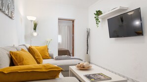 A modern living room with a sofa, a coffee table, a flat-screen TV, and a wall-mounted shelf with a plant. - CAN BLAU - Cosy chalet with garden and terraces near the beach. Free WiFi (Alcúdia)