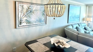 A living room with a chandelier, a sofa, and a dining table with placemats. - MVG 509 Oceanfront Club floor (North Myrtle Beach)