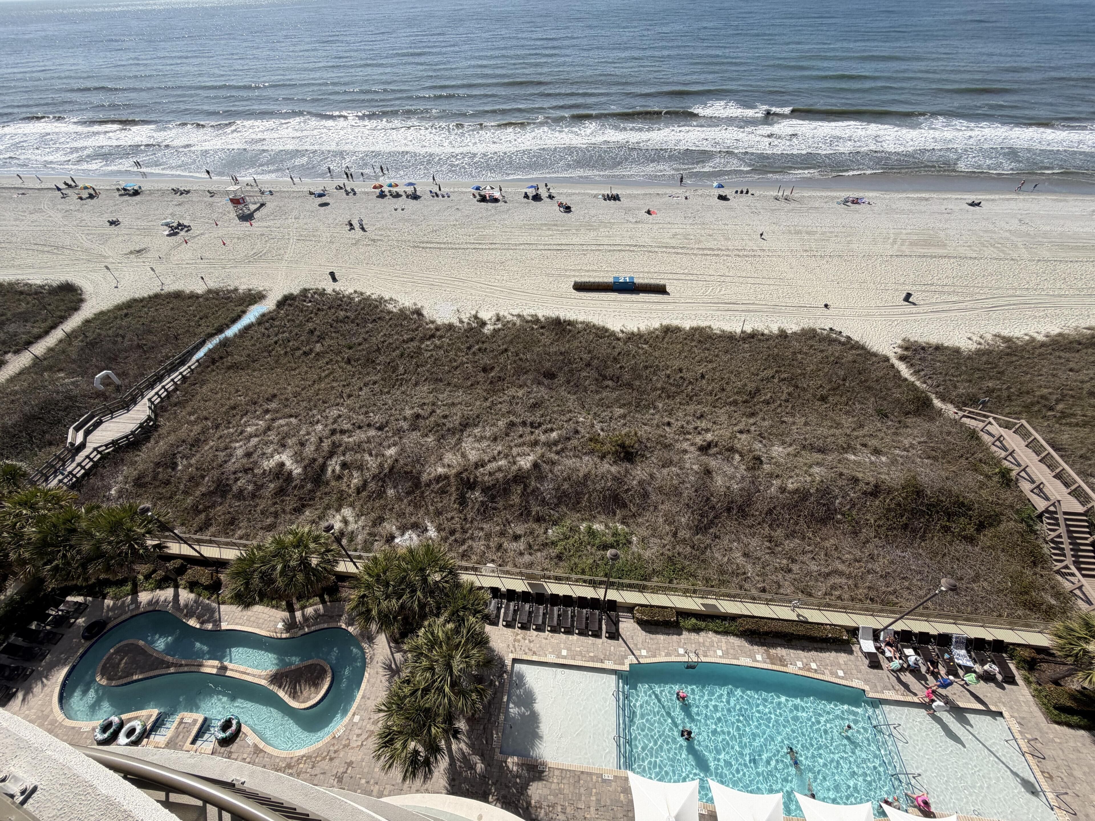Ein Strandresort mit Schwimmbad, Promenade und Strand.