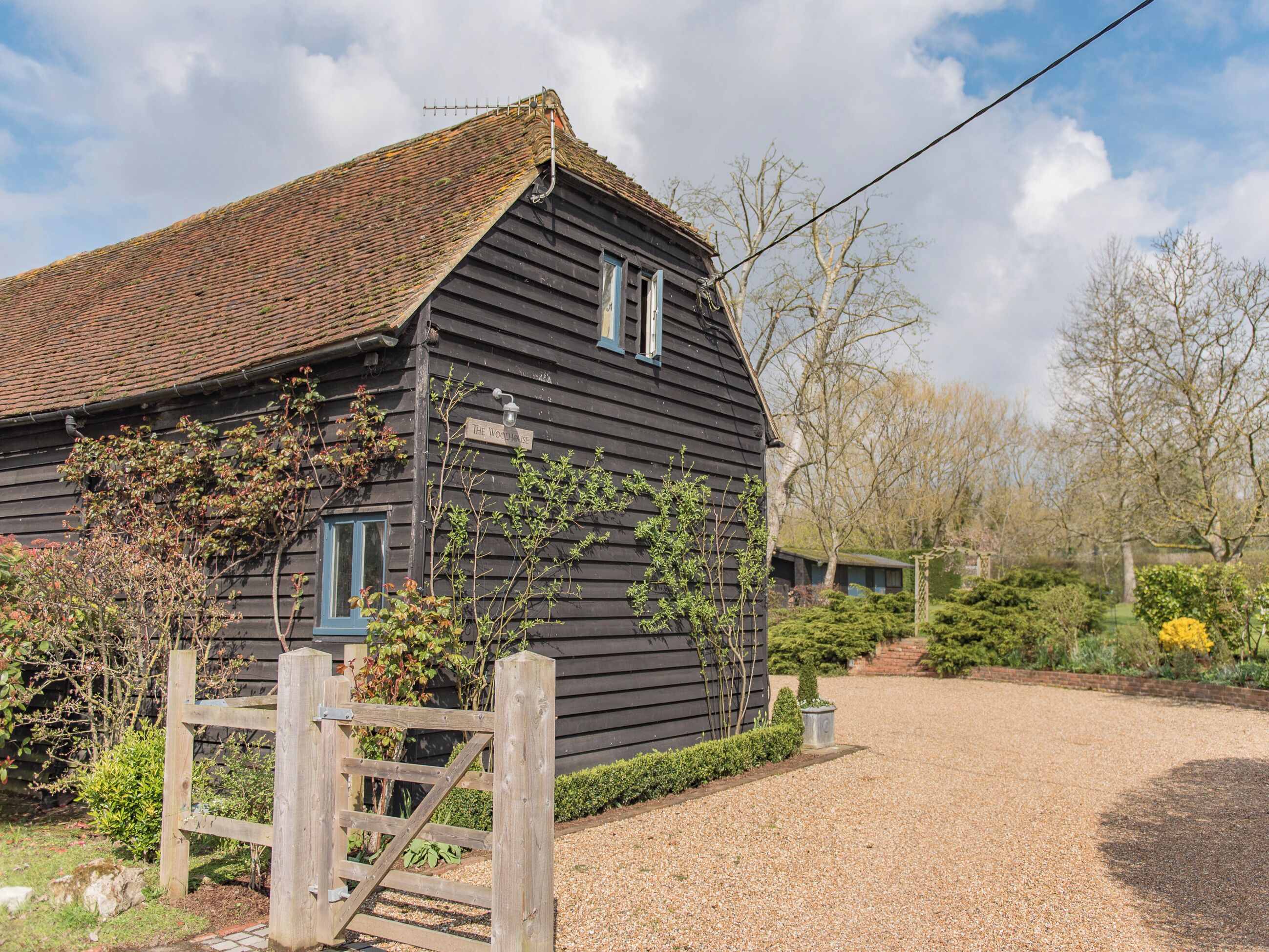 A rustic wooden house with a gravel driveway and a wooden gate.