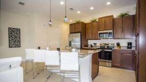 Une cuisine moderne dotée d’un îlot central, d’appareils électroménagers en acier inoxydable et de meubles de rangement en bois.