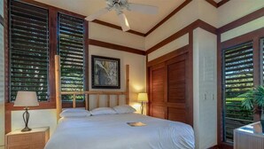 A bedroom with a large bed, wooden headboard, two bedside lamps, a ceiling fan, and a window with blinds. - Poipu Ground Floor Ease w/Kitchen – Kiahuna 2089 (KOLOA)