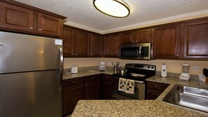 Fully equipped kitchen with stainless steel appliances, granite countertops, and dark cabinetry.