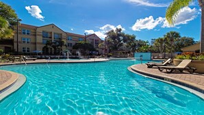 Ein Swimmingpool mit Liegestühlen und einem Gebäude im Hintergrund.