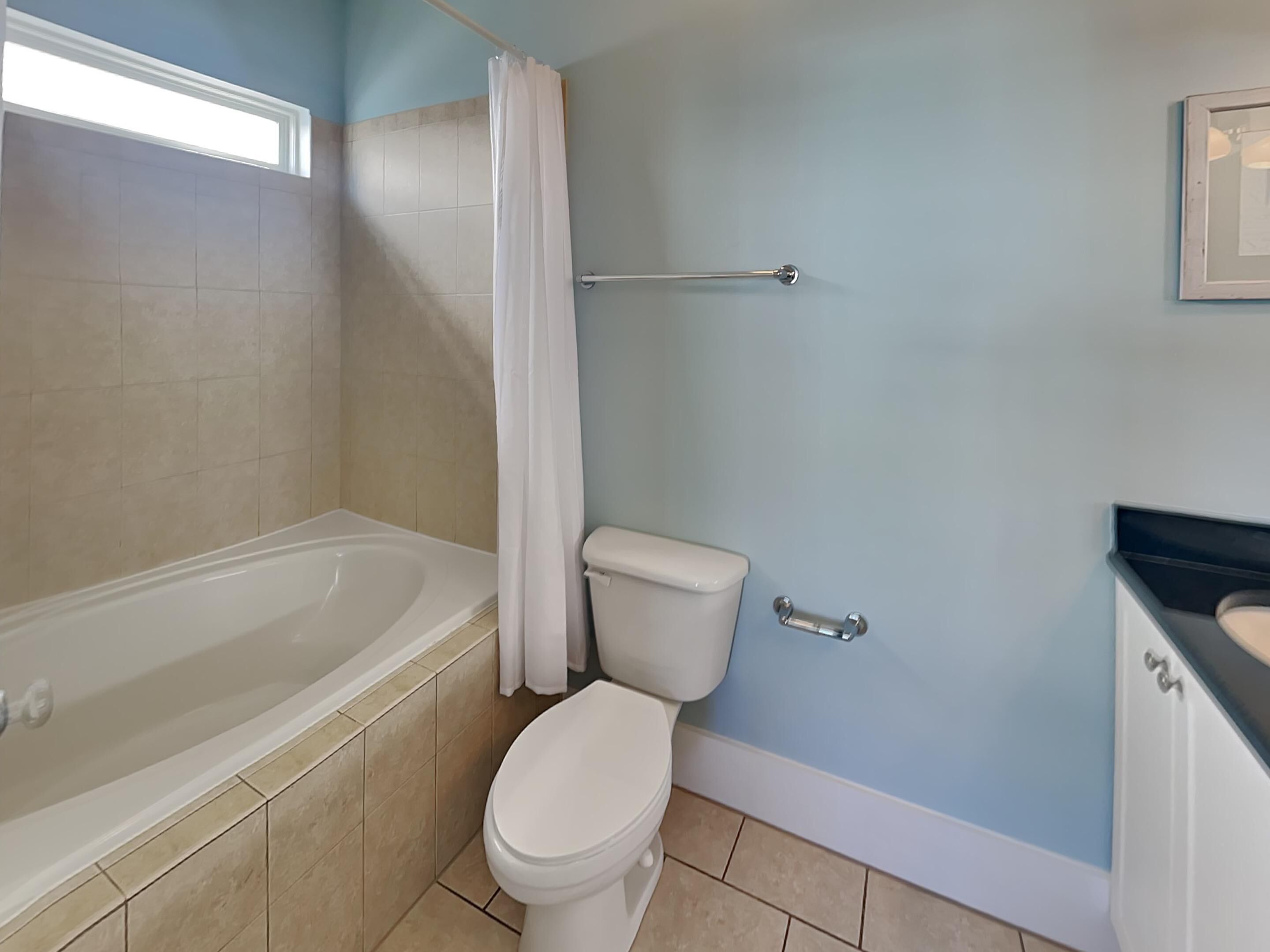 A bathroom with a bathtub, toilet, and a towel rack.