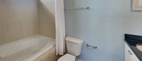 A bathroom with a bathtub, toilet, and a towel rack.