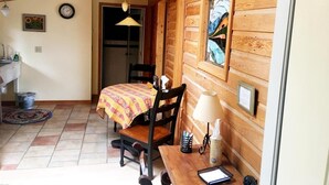 Acogedora habitación tipo cabaña de madera con una cama, una mesa con lámpara, una silla, un reloj y una ventana con un cuadro.