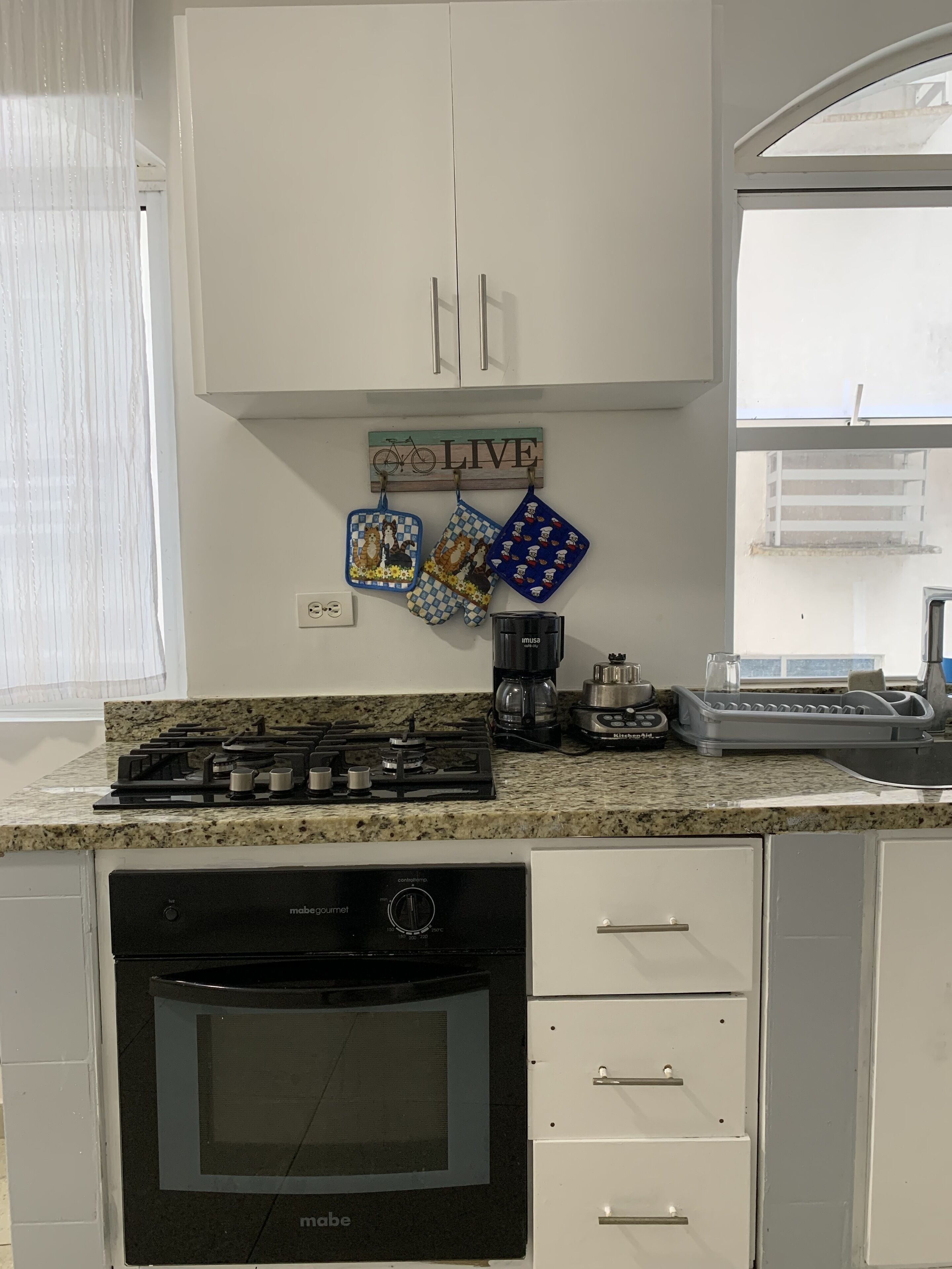 A kitchen with white cabinets, a gas stove, a dishwasher, and a coffee maker.