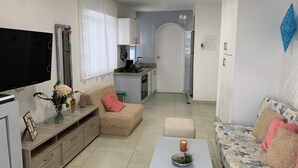 Ein modernes Wohnzimmer mit einer Couch, einem Couchtisch mit Kerze und einem Fernseher.