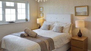 Makuuhuone, jossa on sänky, yöpöydät, kattokruunu ja ikkuna.