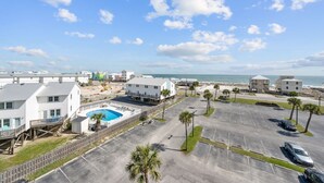 A coastal hotel with a swimming pool, parking area, and ocean view. - Cozy Condo w/ Gulf Views | Boat-Friendly, Pool, Hot Tub, and Tennis Courts (Gulf Shores)