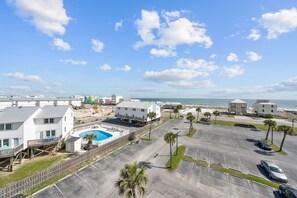 Een hotel aan de kust met een zwembad, parkeerplaats en uitzicht op de oceaan.