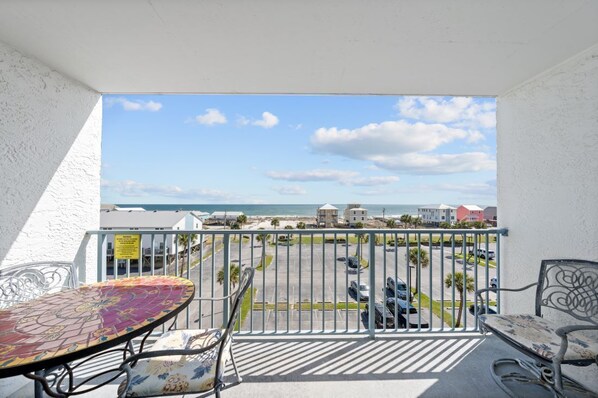 Un balcon avec vue sur la plage et les bâtiments.