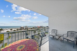 Un balcon avec vue sur la plage et l’océan, comprenant une table et deux chaises.