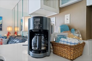 A coffee maker on a counter with a basket of snacks and a bag labeled "Young's Suncoast Realty."